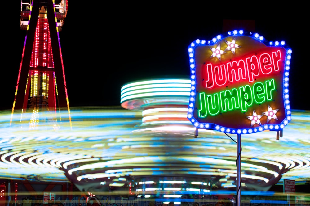 a carnival sign and a ferris wheel at night