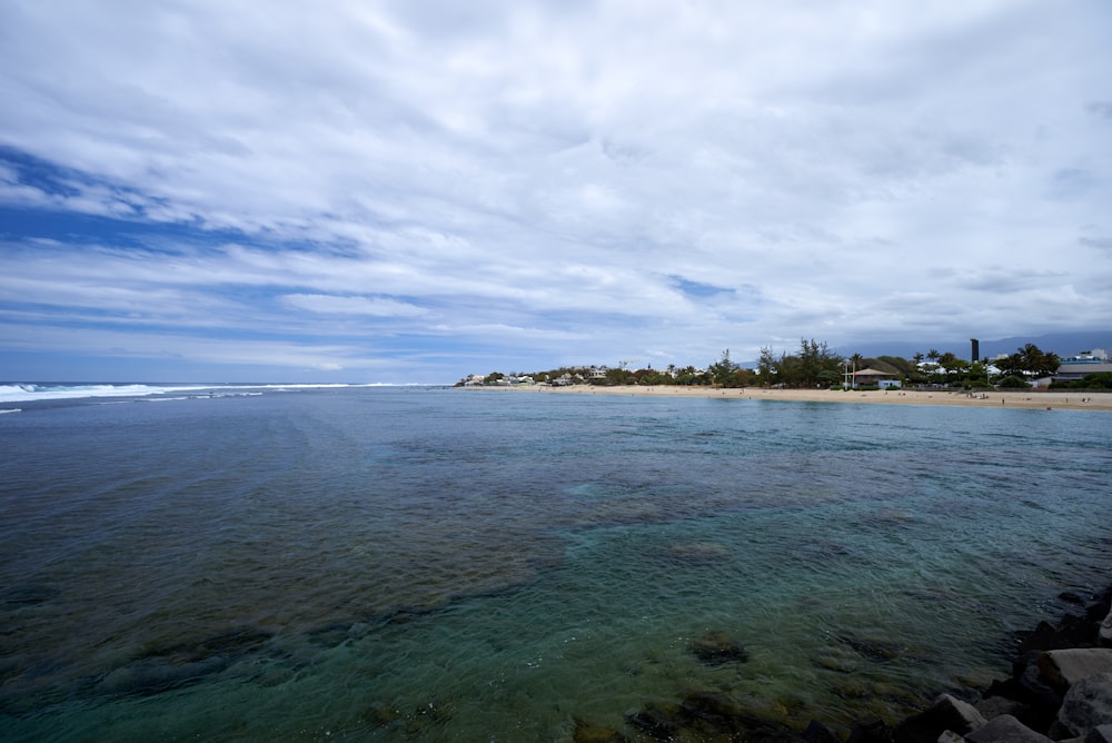 green trees on island under white clouds and blue sky during daytime