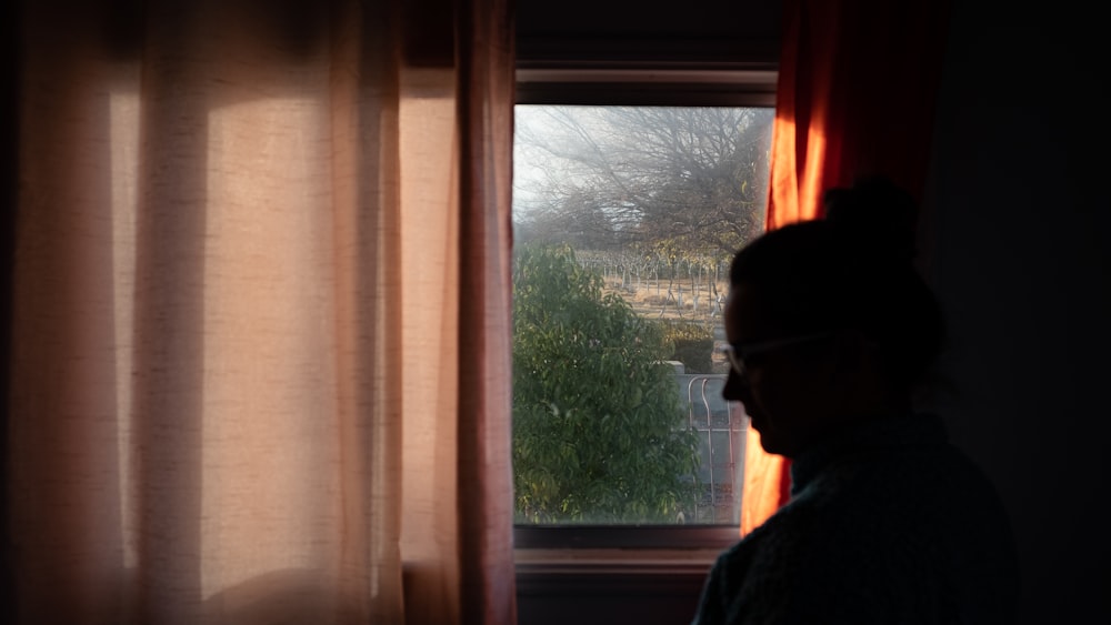 person in blue jacket standing near window