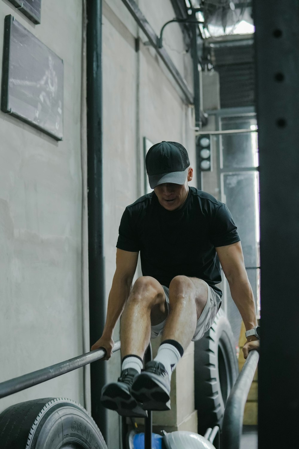 man in black crew neck t-shirt and white shorts sitting on gray concrete bench