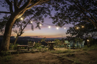 A serene outdoor seating area surrounded by greenery and soft lighting at dusk.