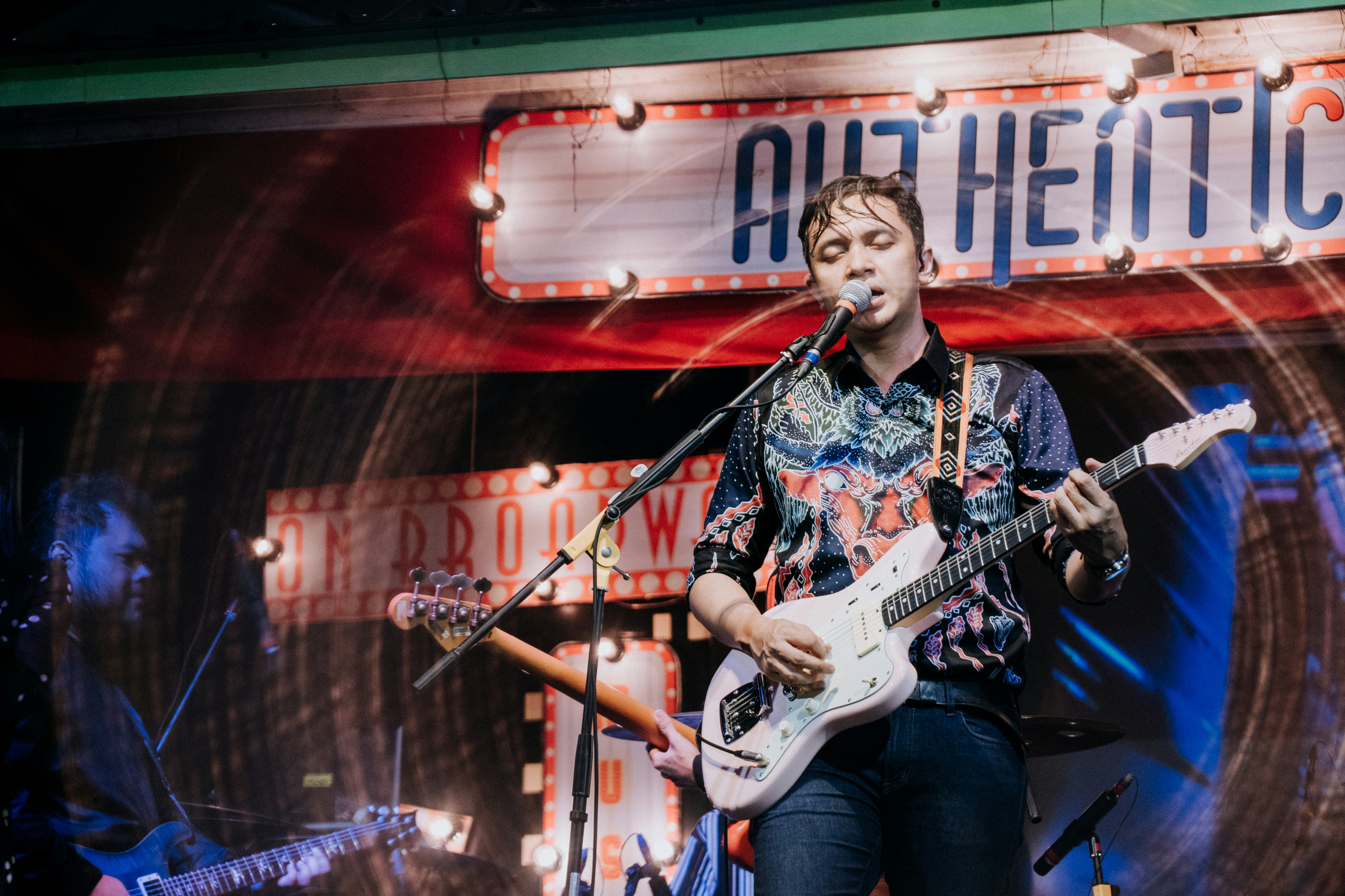 man in black and white floral button up shirt playing electric guitar