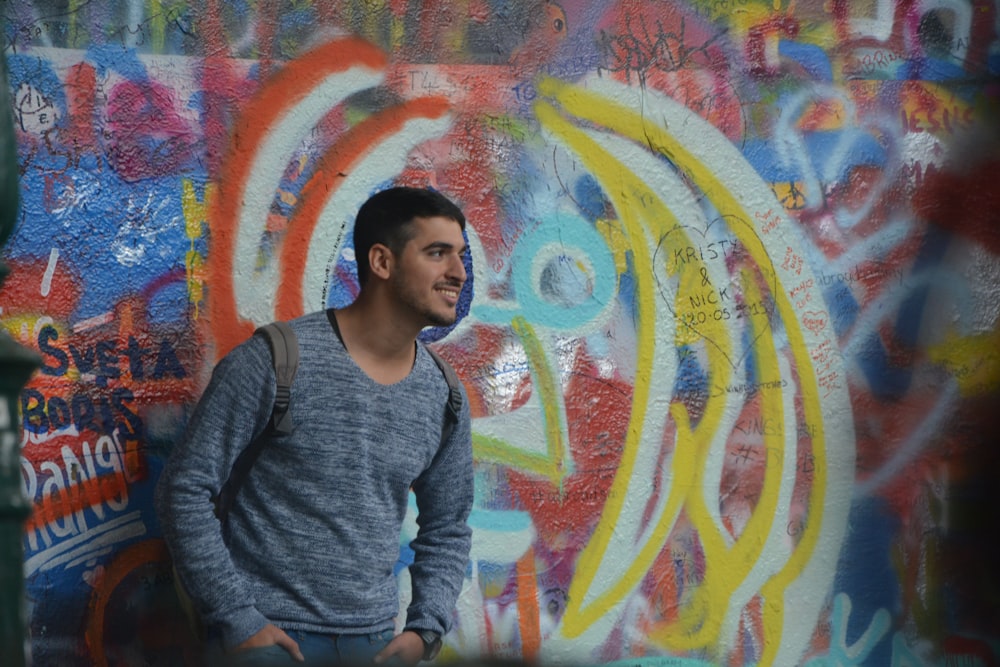 woman in gray long sleeve shirt standing beside wall with graffiti