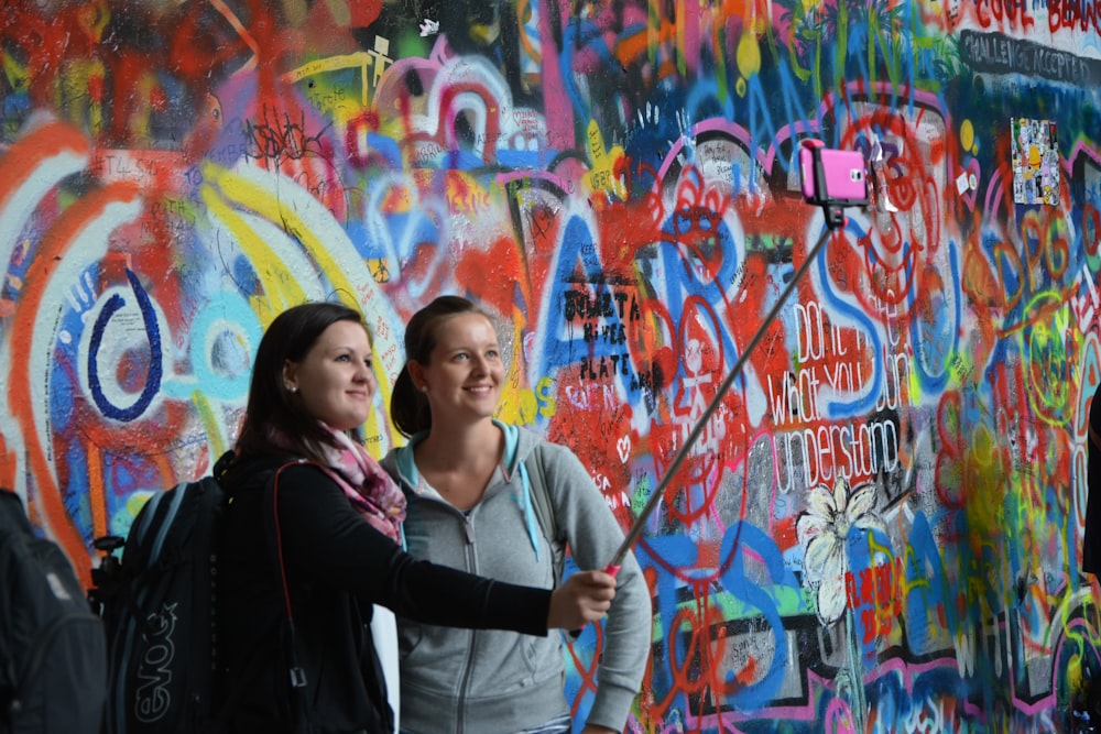 woman in black and white jacket standing beside wall with graffiti