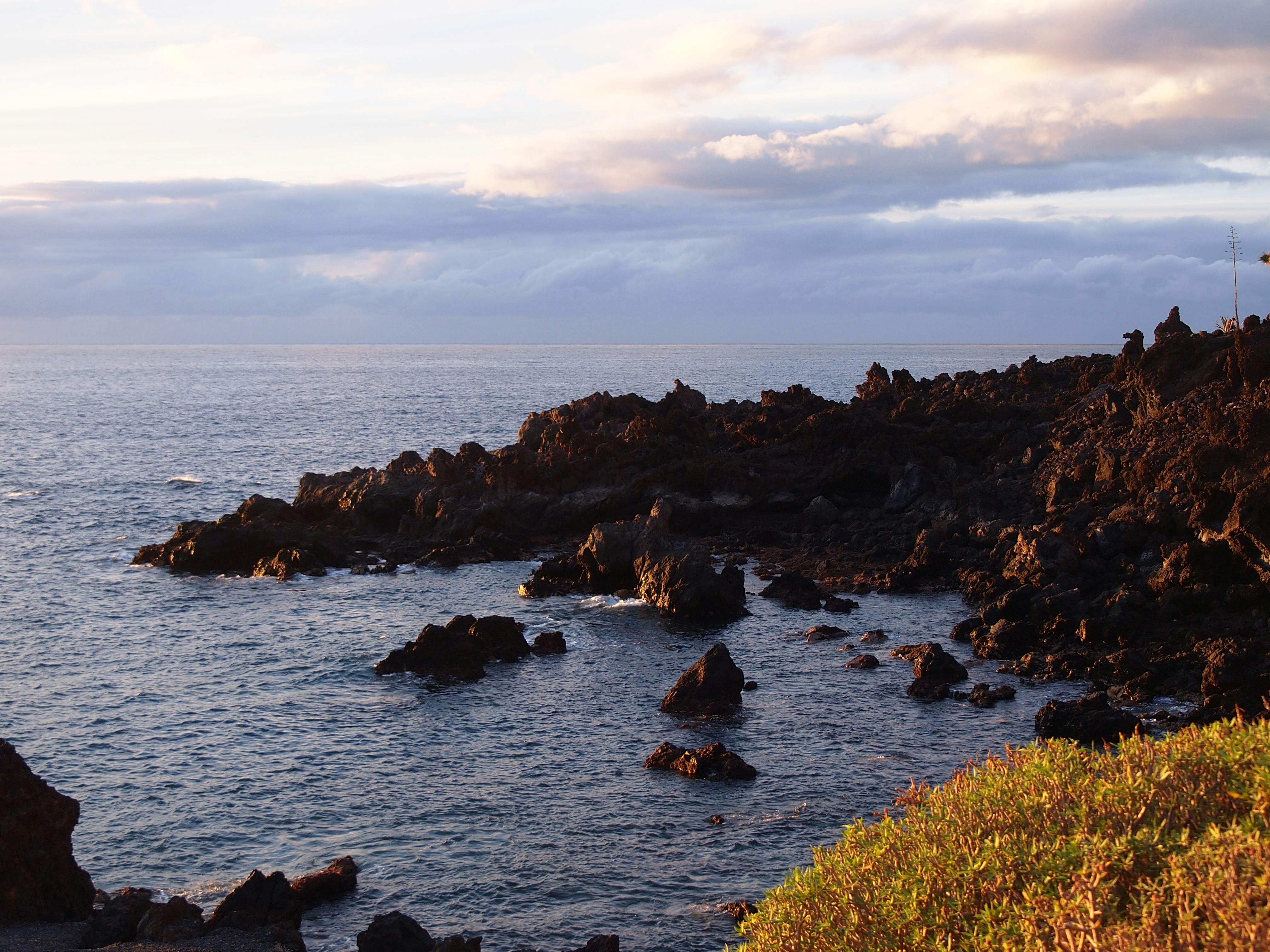 brown rocks on sea under white clouds during daytime