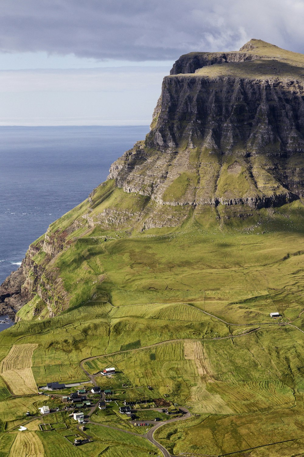 green grass covered mountain beside sea during daytime