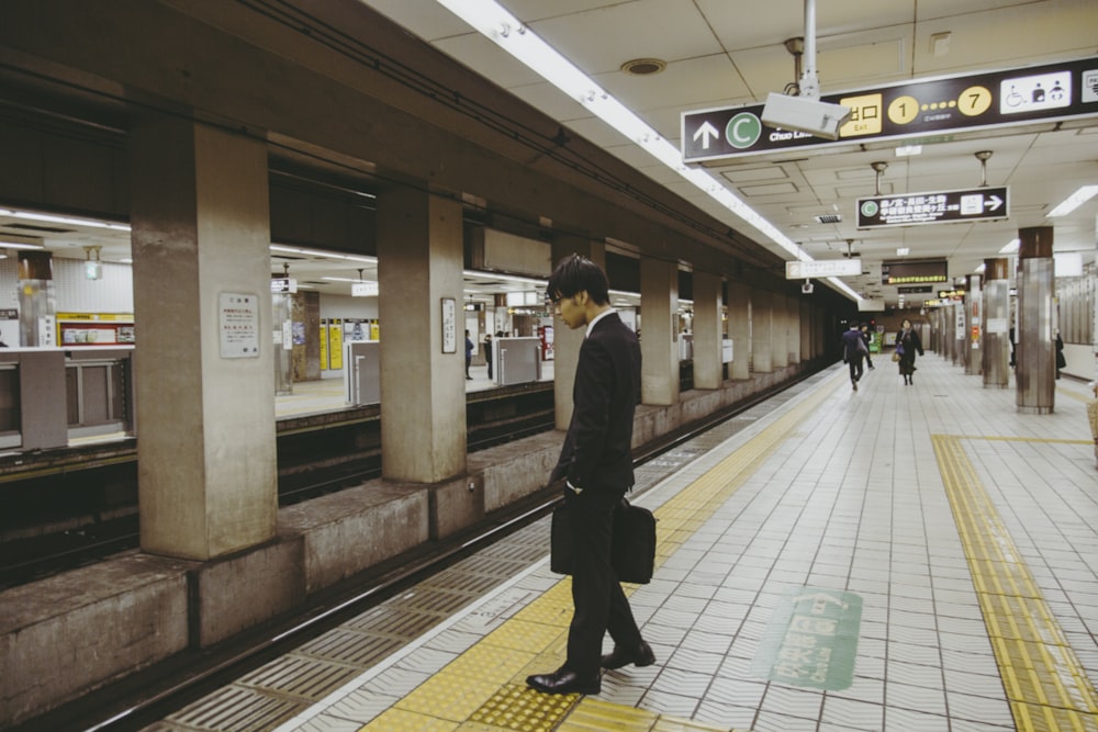 man in black jacket walking on train station