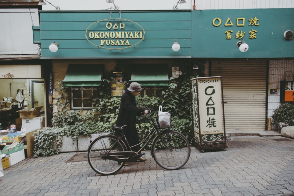 man in black jacket riding bicycle near store during daytime