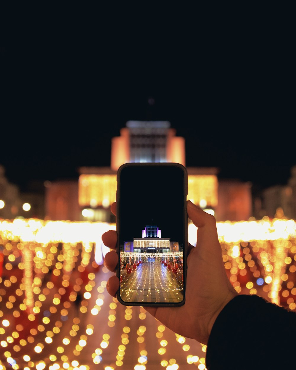 person holding black smartphone taking photo of city lights during night time