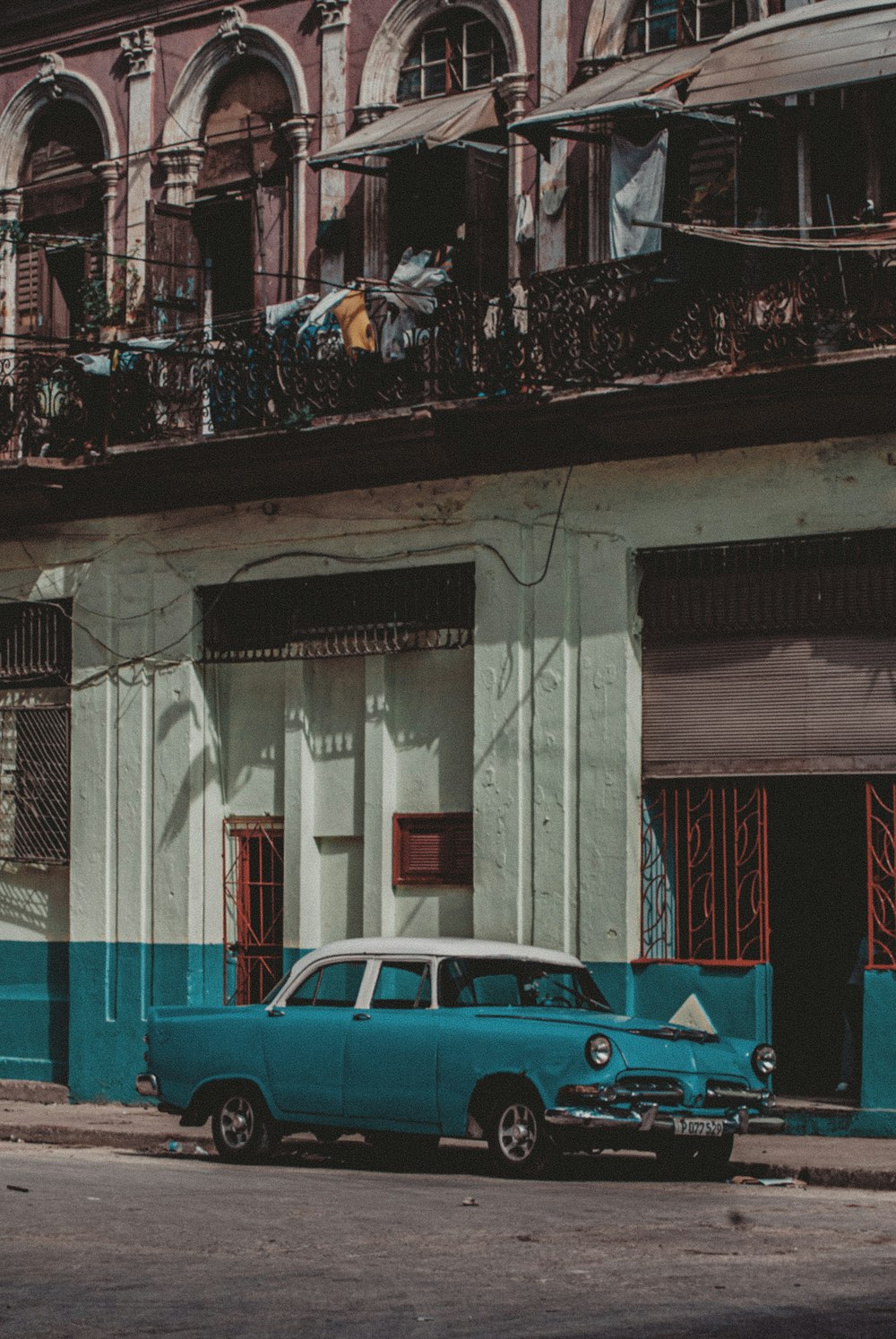 blue sedan parked beside white concrete building during daytime