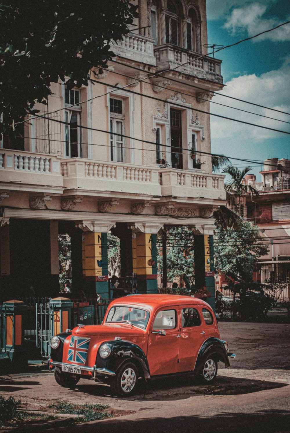 red volkswagen beetle parked beside brown concrete building during daytime