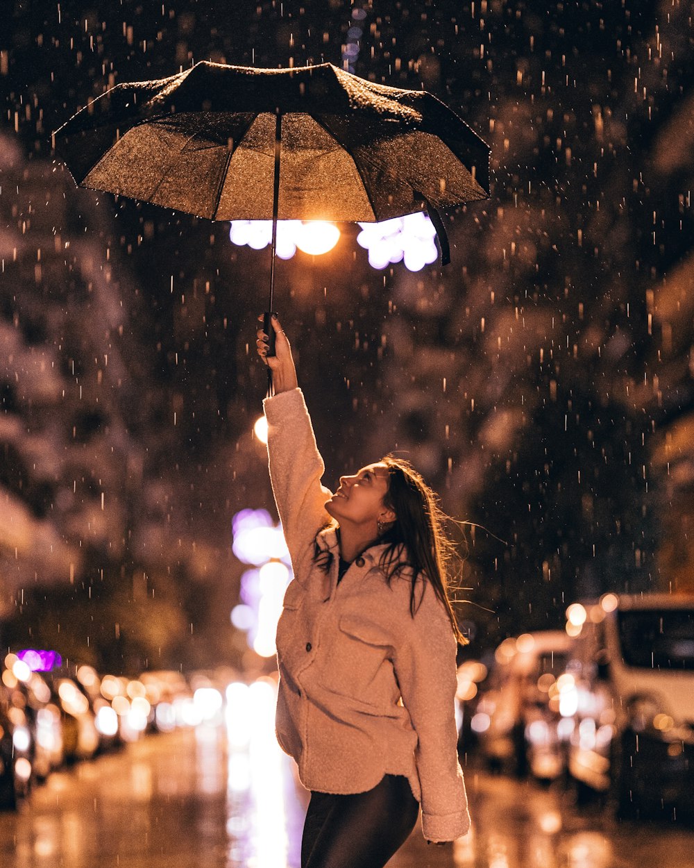 woman in brown coat holding umbrella during night time