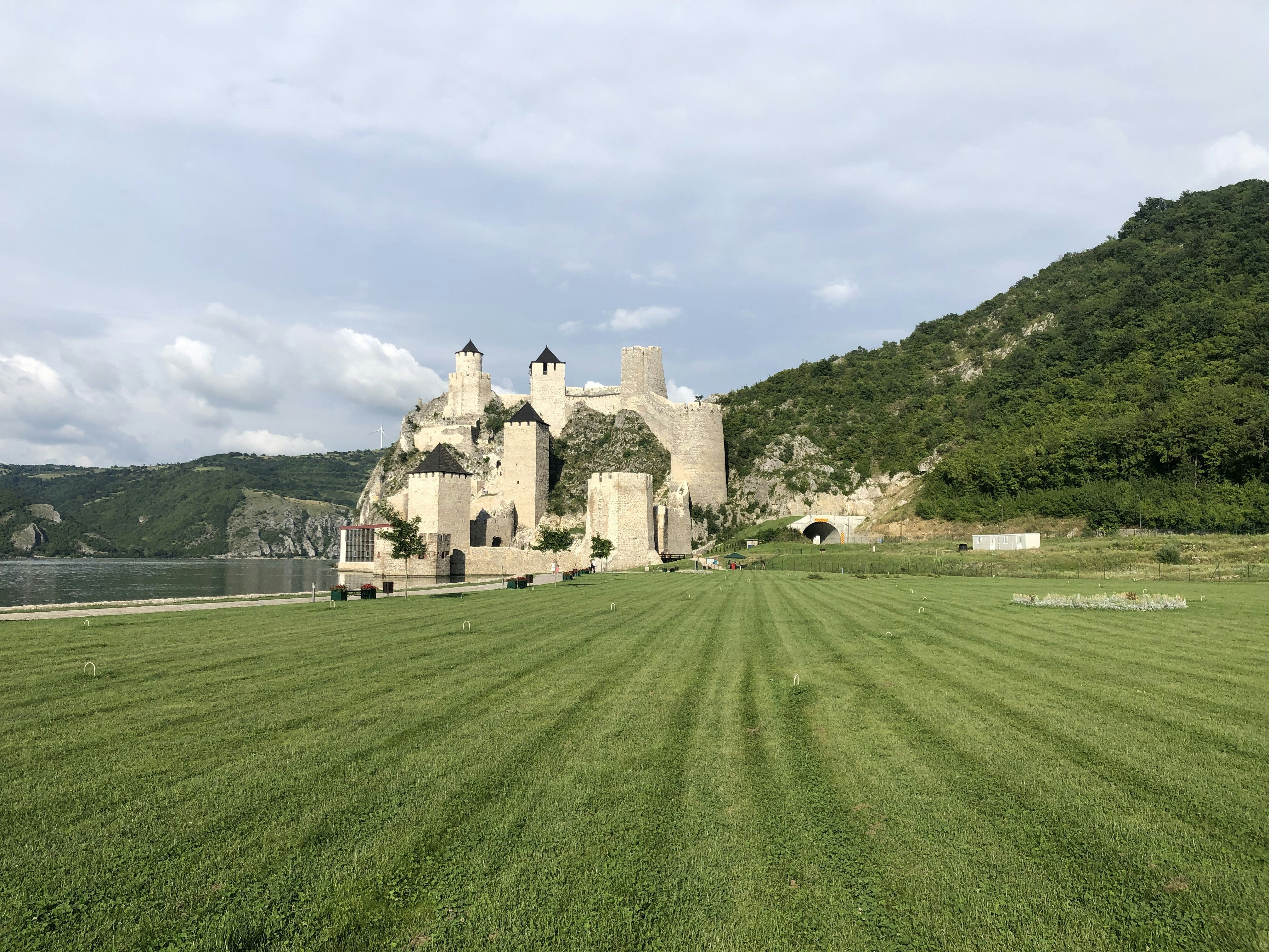 brown concrete building on green grass field under white clouds during daytime