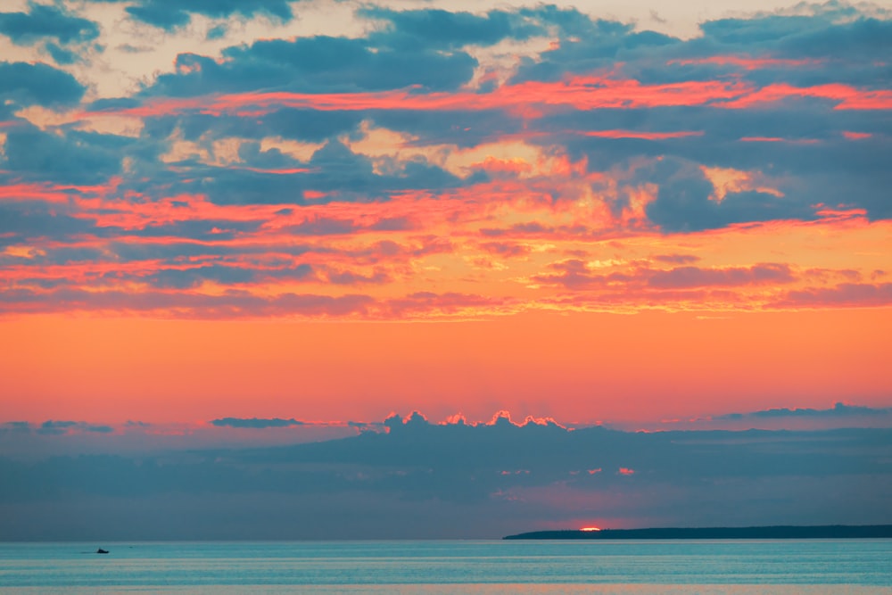 body of water under orange and blue sky during sunset