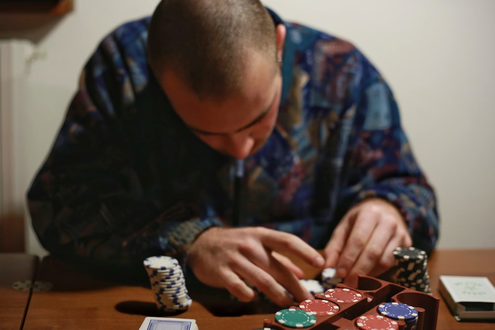 Hombre con camisa de manga larga azul y negra jugando al ajedrez