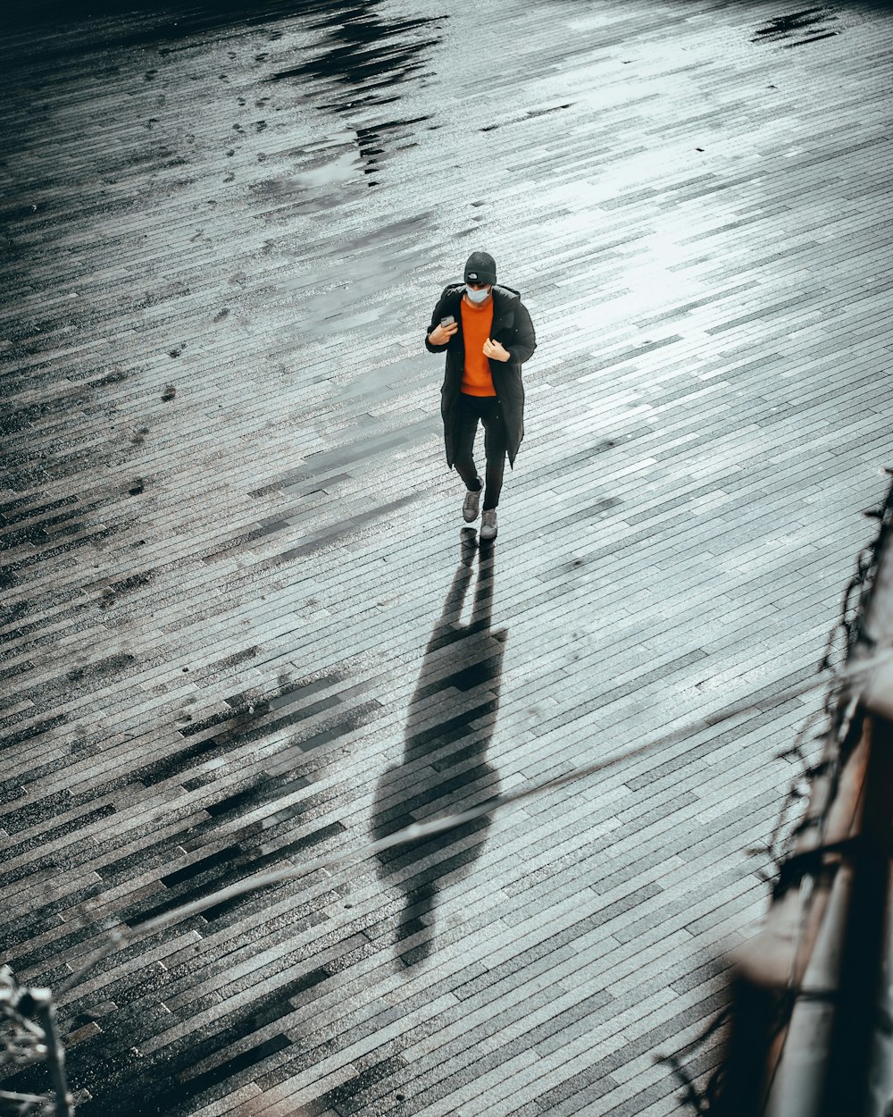 man in black jacket and black pants walking on wooden dock during daytime