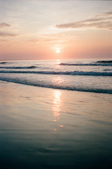sea waves crashing on shore during sunset