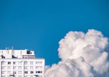Ultra-realistic 4K render of a luxury apartment complex with soft light gray and white tones under a clear sky.