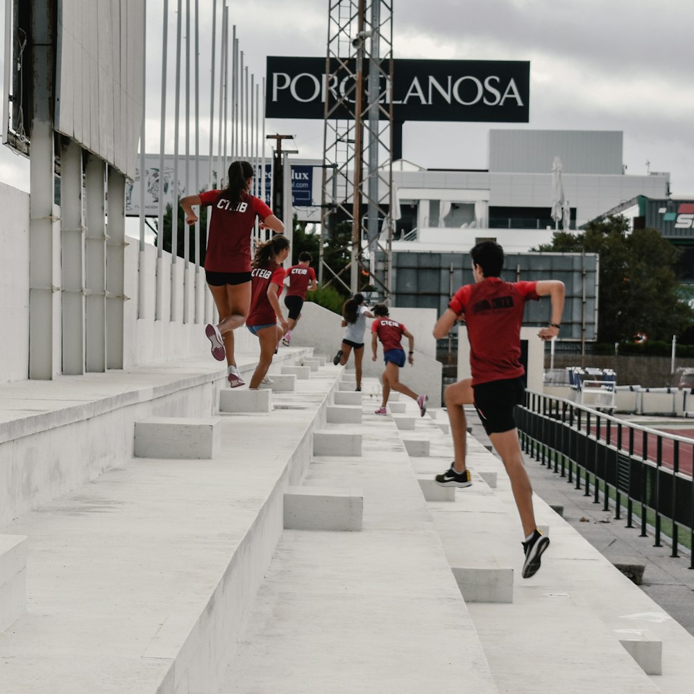 man in red t-shirt and black shorts walking on sidewalk during daytime