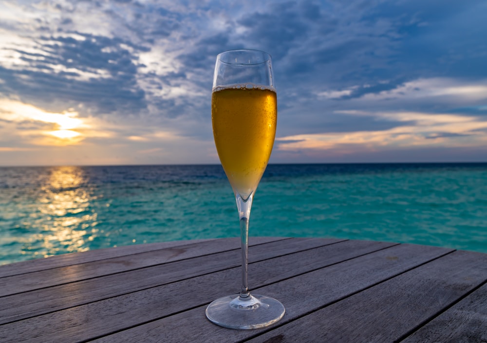 clear wine glass with yellow liquid on brown wooden table