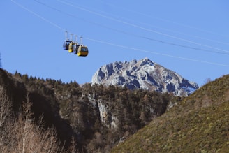 Cable cars ascending over a mountainous landscape with clear blue skies.
