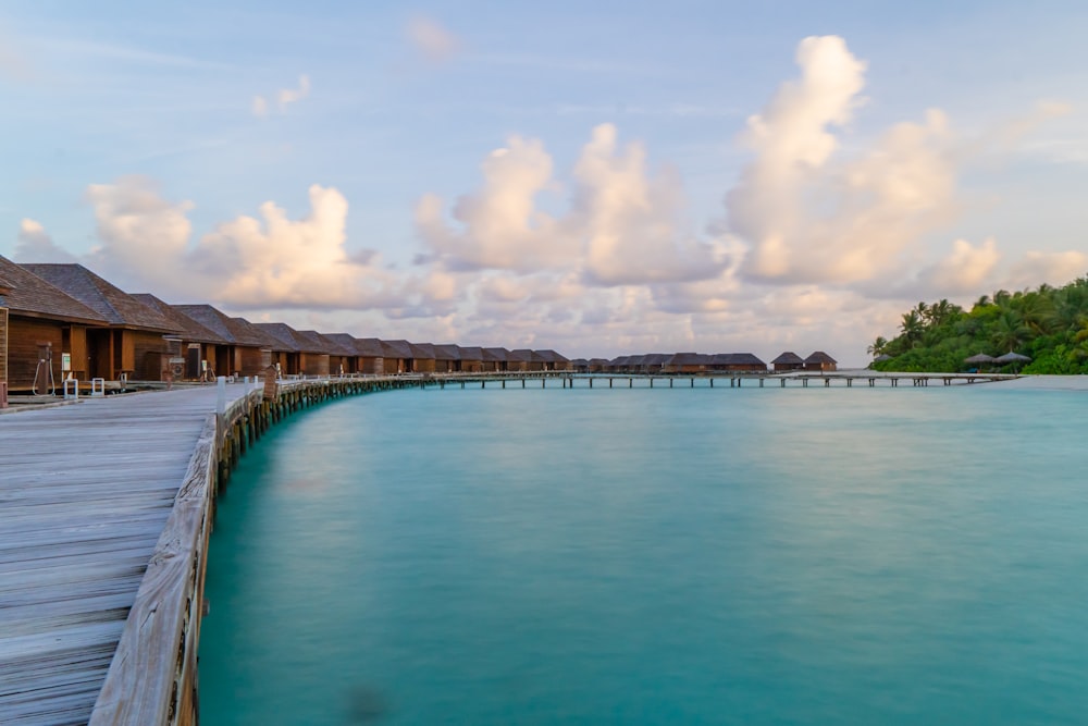 gray concrete bridge over blue sea under blue sky and white clouds during daytime