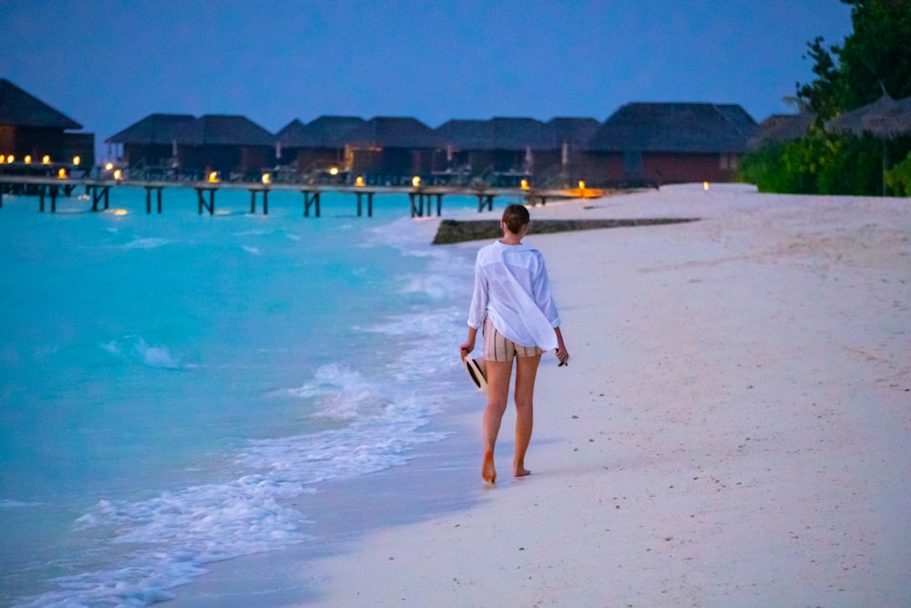 woman in white dress walking on beach during daytime