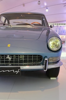A classic car with a sleek, vintage design featuring a prominent grille and round headlights. The car is blue in color and appears to be well-maintained, reflecting a sense of elegance and nostalgia.
