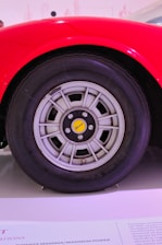 Close-up of a vibrant red pkl centre cap fitted on a sleek VW wheel under natural sunlight.