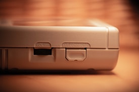 Close-up view of a vintage electronic device featuring a volume control and a port labeled 'EXT. CONNECTOR' on a beige textured surface. The lighting creates a warm, nostalgic atmosphere.