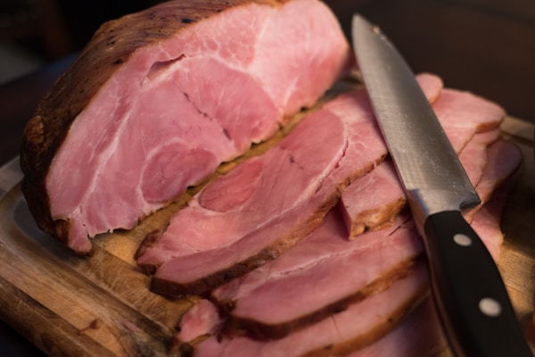 Sliced meat on brown wooden chopping board