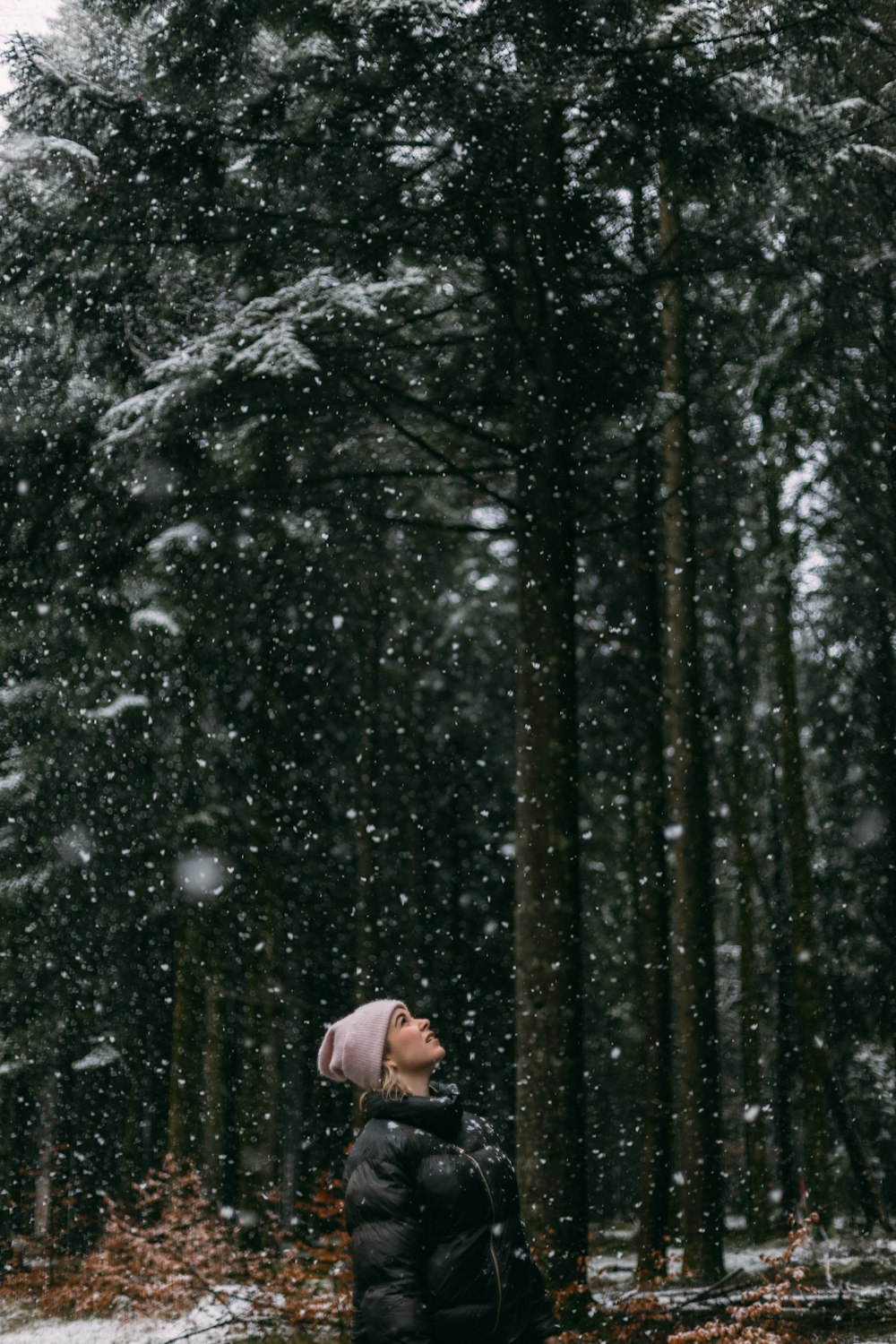 Person in weißer Jacke, die tagsüber in der Nähe von Bäumen steht