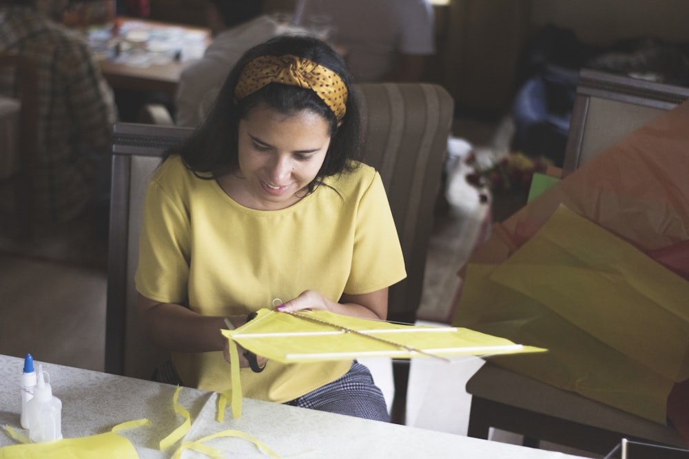 girl in yellow crew neck t-shirt sitting on white chair