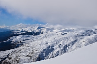 snow covered mountain under cloudy sky during daytime