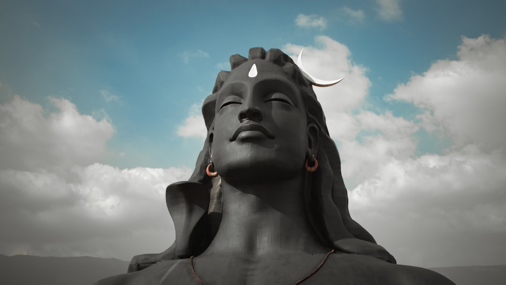 estátua de concreto cinzenta sob o céu azul durante o dia