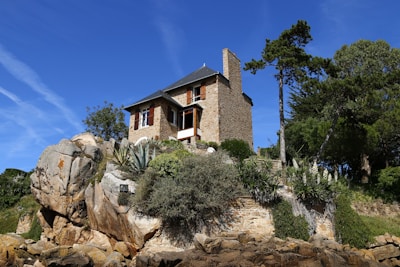 brown concrete house near green trees under blue sky during daytime