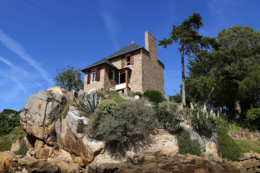 brown concrete house near green trees under blue sky during daytime