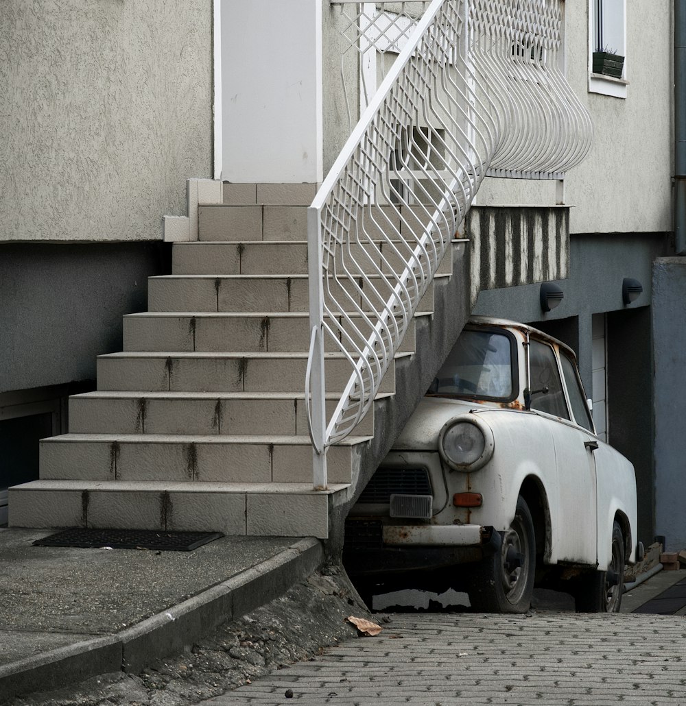 white car parked beside white concrete staircase