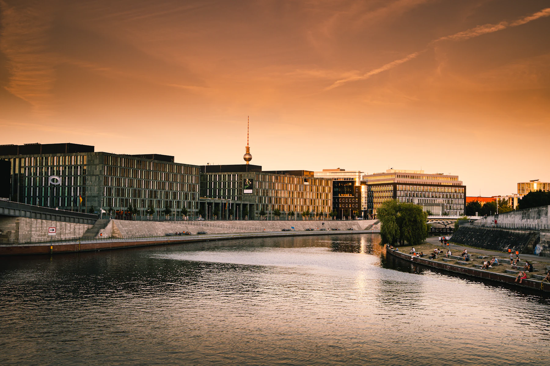 The Spree River in Berlin at golden hour with the TV tower glowing against an orange sky