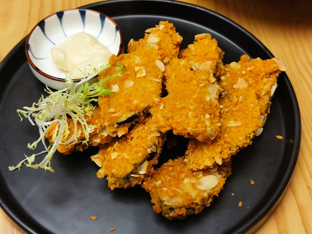 fried food with white cream on black plate