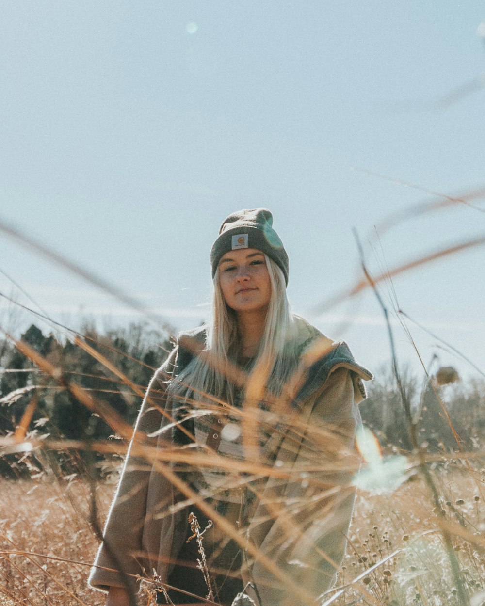 woman in brown and black scarf standing on brown dried grass during daytime