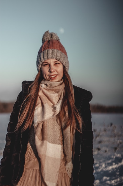 A model wearing a soft, oversized knit sweater and scarf, standing against a snowy backdrop.
