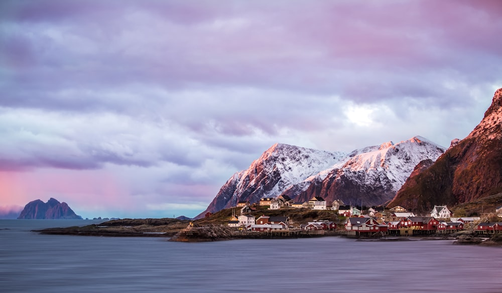 brown and white mountain near body of water under cloudy sky during daytime