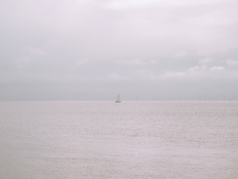 sailboat on sea under white sky during daytime