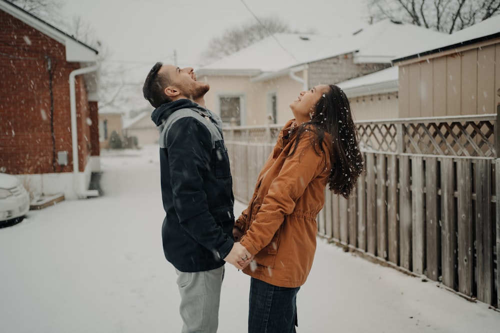 man in black jacket and woman in brown coat standing on snow covered ground during daytime