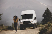 woman in black tank top and white shorts standing beside white van during daytime