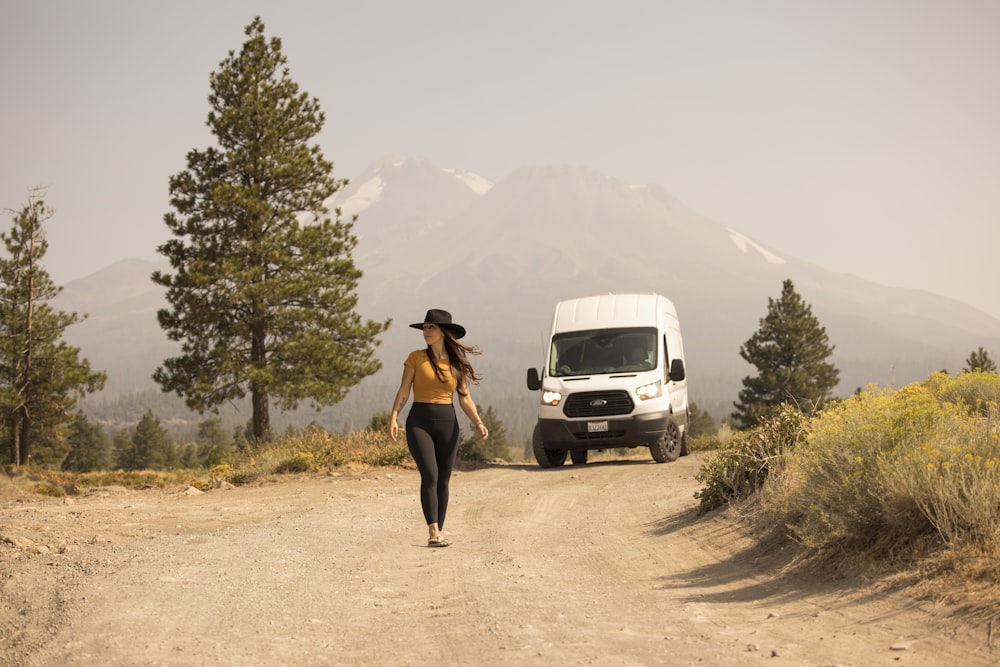 man in black pants standing beside white suv during daytime