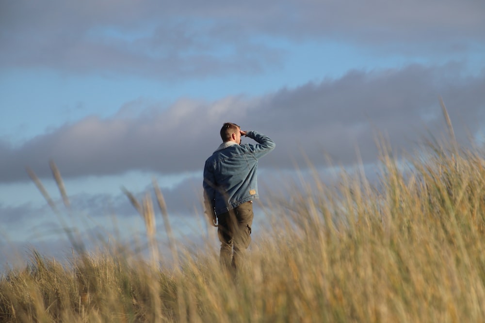homem em hoodie cinza em pé no campo de grama marrom durante o dia