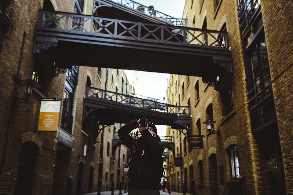 man in black jacket standing on bridge during daytime