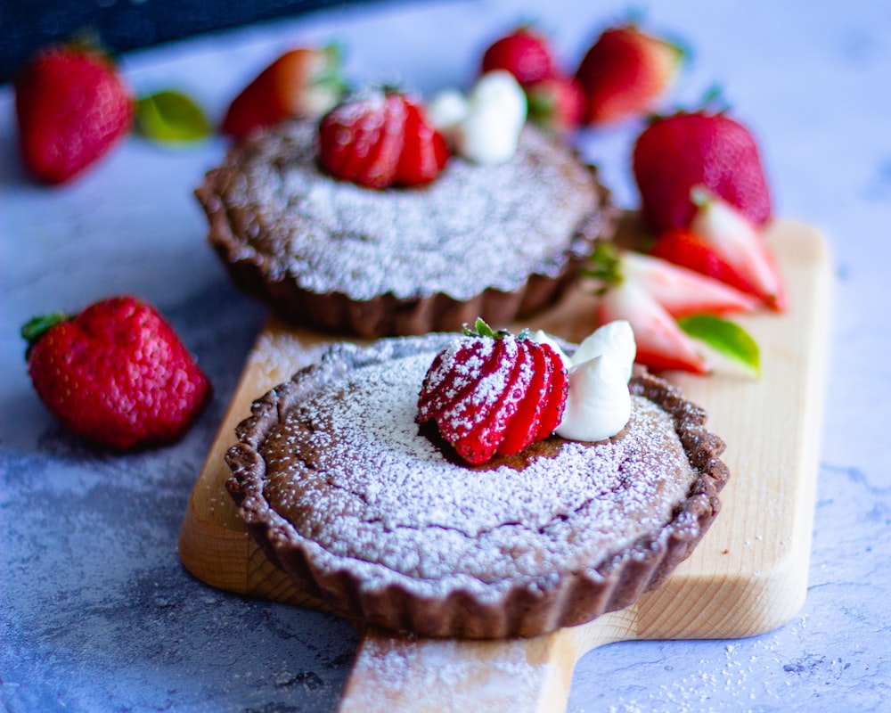 a couple of desserts sitting on top of a wooden cutting board